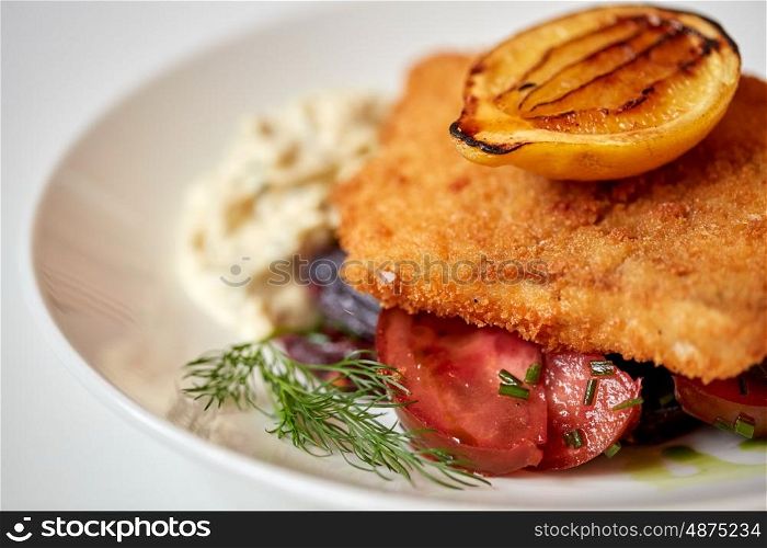 food, new nordic cuisine, culinary and cooking concept - close up of breaded fish fillet with tartar sauce and oven-baked beetroot tomato salad on plate