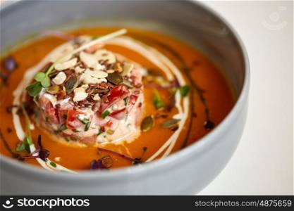 food, new nordic cuisine, culinary and cooking concept - close up of vegetable pumpkin-ginger soup with goat cheese and tomato salad with yogurt in bowl