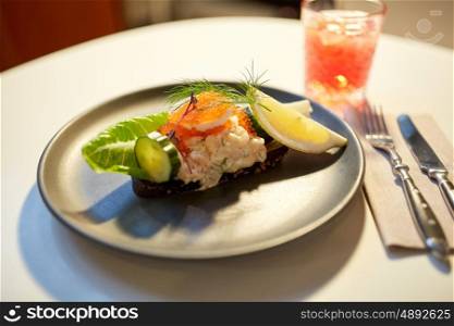 food, new nordic cuisine, culinary and cooking concept - close up of toast skagen with shrimps, fish roe and buttery bread on plate at restaurant