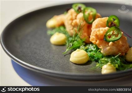 food, new nordic cuisine, culinary and cooking concept - close up of king prawns with jalapeno, wasabi mayonnaise and wakame salad on plate
