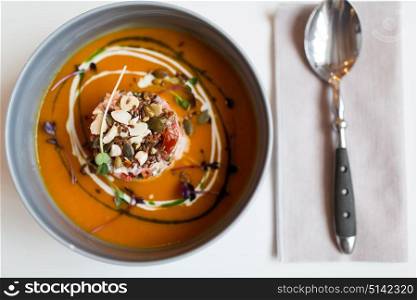 food, new nordic cuisine, culinary and cooking concept - close up of vegetable pumpkin-ginger soup with goat cheese and tomato salad with yogurt in bowl. close up of vegetable pumpkin-ginger soup in bowl