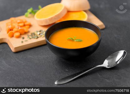 food, new nordic cuisine, culinary and cooking concept - close up of vegetable pumpkin cream soup in bowl and spoon on stone table. close up of vegetable pumpkin cream soup in bowl