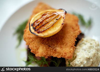 food, new nordic cuisine, dinner, culinary and cooking concept - close up of breaded fish fillet with tartar sauce and oven-baked beetroot tomato salad on plate