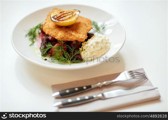 food, new nordic cuisine, dinner, culinary, haute cuisine and cooking concept - close up of breaded fish fillet with tartar sauce and oven-baked beetroot tomato salad on plate
