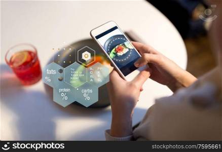 food, new nordic cuisine, technology and people concept - close up of hand with toast skagen on smartphone screen and nutritional value chart at restaurant. hands with phone and food nutritional value chart