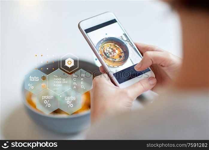food, new nordic cuisine, technology, eating and people concept - close up of hands with bowl of vegetable pumpkin-ginger soup on smartphone screen and nutritional value chart at restaurant. hands with phone and food nutritional value chart
