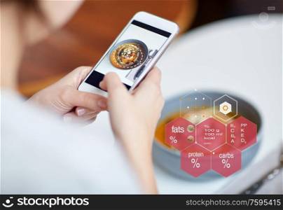 food, new nordic cuisine, technology, eating and people concept - close up of hands with bowl of vegetable pumpkin-ginger soup on smartphone screen and nutritional value chart at restaurant. hands with phone and food nutritional value chart
