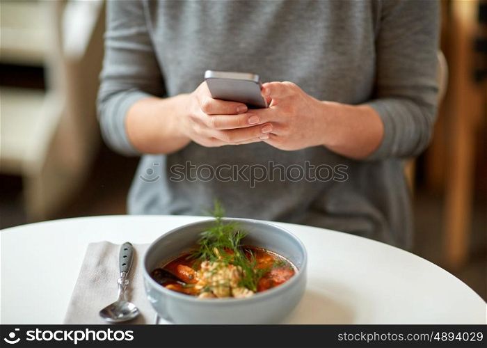 food, new nordic cuisine, technology, eating and people concept - woman sitting at cafe table with smartphone and bowl of soup