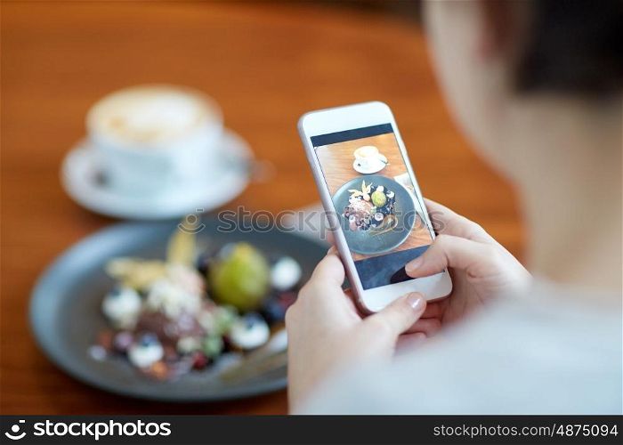 food, new nordic cuisine, technology, eating and people concept - woman with smartphone photographing chocolate ice cream dessert with blueberry kissel, honey baked fig and greek yoghurt at cafe