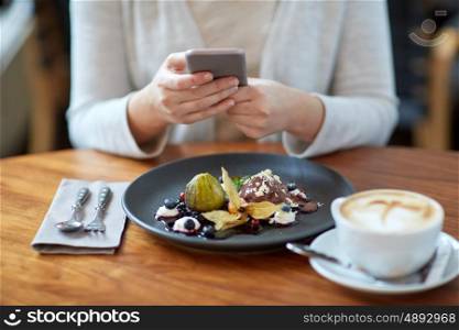food, new nordic cuisine, technology, eating and people concept - woman with smartphone, chocolate ice cream dessert with blueberry kissel, honey baked fig and yoghurt and coffee sitting at cafe table
