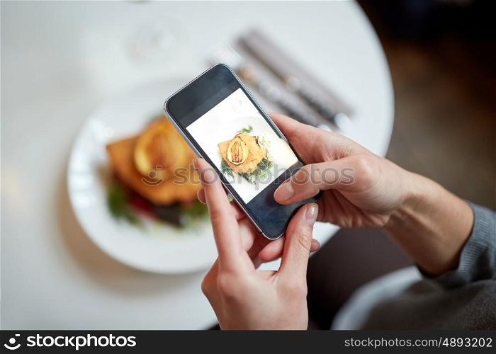 food, new nordic cuisine, technology, eating and people concept - woman with smartphone photographing breaded fish fillet with tartar sauce and oven-baked beetroot tomato salad at restaurant