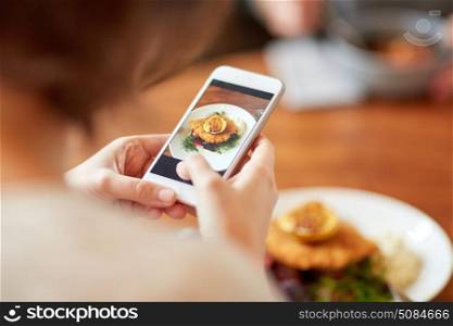 food, new nordic cuisine, technology, eating and people concept - woman with smartphone photographing breaded fish fillet with tartar sauce and oven-baked beetroot tomato salad at restaurant. woman with smartphone photographing food at cafe. woman with smartphone photographing food at cafe