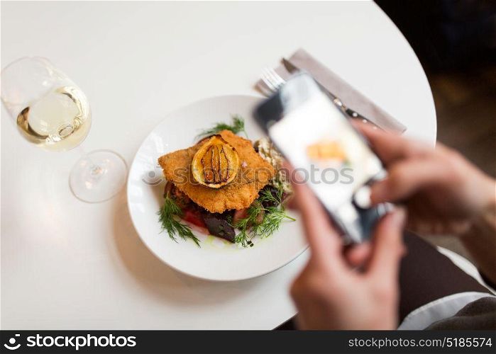 food, new nordic cuisine, technology, eating and people concept - woman with smartphone photographing breaded fish fillet with tartar sauce and oven-baked beetroot tomato salad at restaurant. woman with smartphone photographing food at cafe