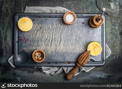 Food or cooking background with salt ,pepper and lemon on gray vintage gutting board, top view