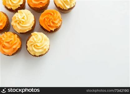 food, pastry and confectionery concept - cupcakes with buttercream frosting over white background. cupcakes with frosting on white background