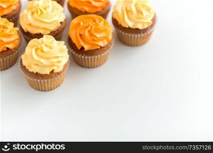 food, pastry and confectionery concept - cupcakes with buttercream frosting over white background. cupcakes with frosting on white background