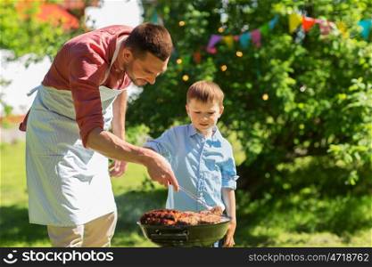 food, people and family time concept - father and son cooking meat on barbecue grill at bbq party in summer garden. father and son cooking meat on barbecue grill. father and son cooking meat on barbecue grill
