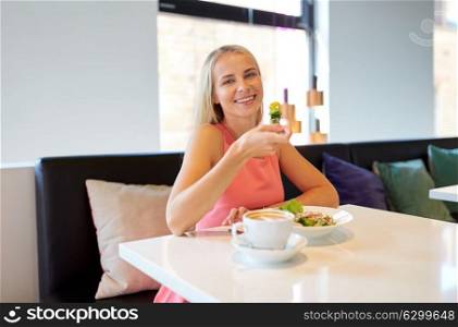 food, people and leisure concept - happy young woman eating salad with coffee for lunch at restaurant. happy young woman eating lunch at restaurant