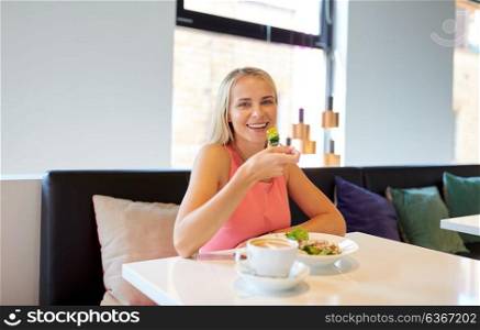 food, people and leisure concept - happy young woman eating salad with coffee for lunch at restaurant. happy young woman eating lunch at restaurant