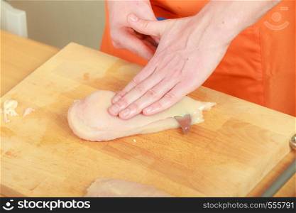 Food preparing, cooking concept. Male hands chef cutting raw chicken meat breast on wooden board close up
