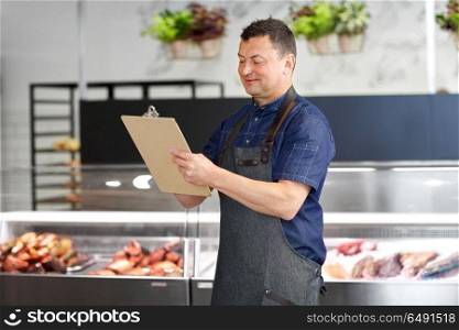 food sale, small business and people concept - male seller at fish shop writing to clipboard. seller at fish shop writing to clipboard. seller at fish shop writing to clipboard