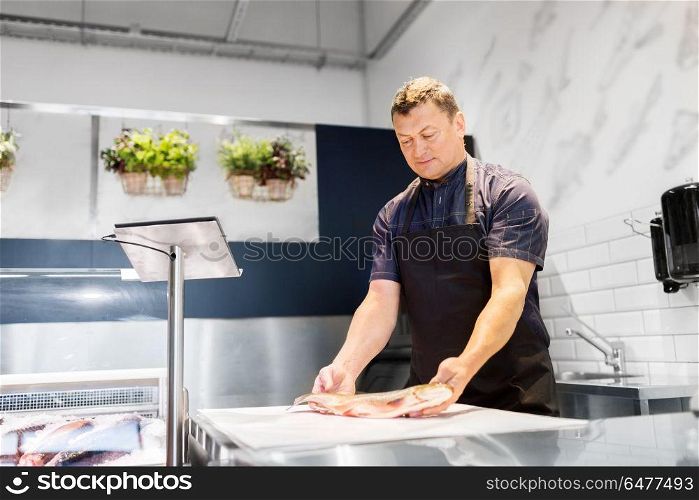 food sale, small business and people concept - male seller weighing fish on scale at seafood shop. seller weighing fish on scale at seafood shop. seller weighing fish on scale at seafood shop