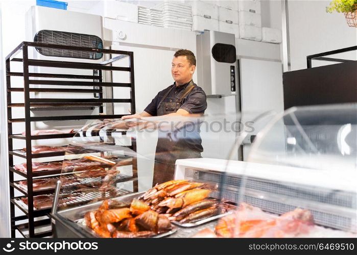 food sale, small business and people concept - male seller with smoking tray at fish shop. seller with smoking tray at fish shop