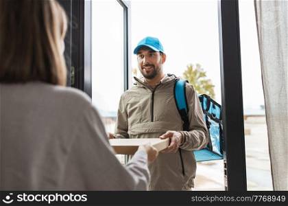 food shipping and people concept - happy delivery man with thermal insulated bag giving pizza box to female customer at home. food delivery man giving order to female customer