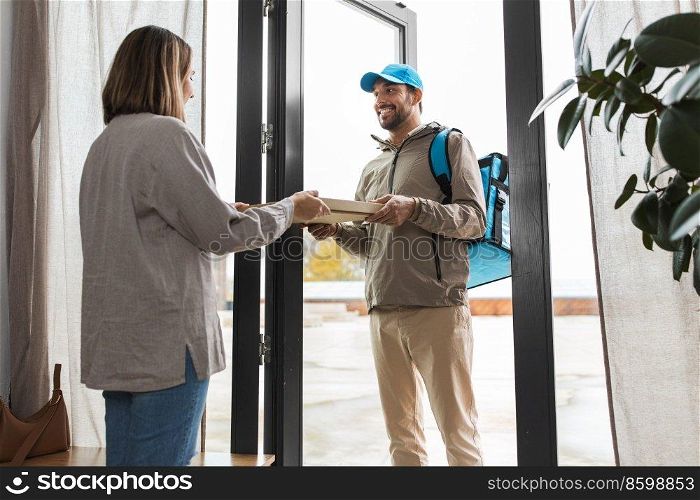 food shipping and people concept - happy delivery man with thermal insulated bag giving pizza box to female customer at home. food delivery man giving order to female customer