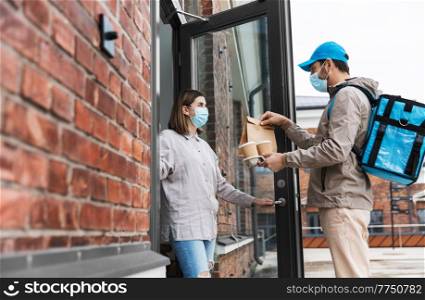 food shipping, pandemic and people concept - delivery man in mask with thermal insulated bag giving order and coffee to female customer at home. food delivery man in mask giving order to customer