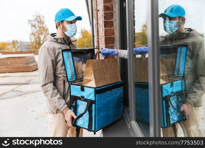 food shipping, pandemic and people concept - delivery man in mask with open thermal insulated bag giving order to customer at home. food delivery man in mask giving order to customer