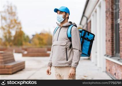 food shipping, pandemic and people concept - delivery man in protective medical mask with thermal insulated bag in city. delivery man in mask with thermal bag in city