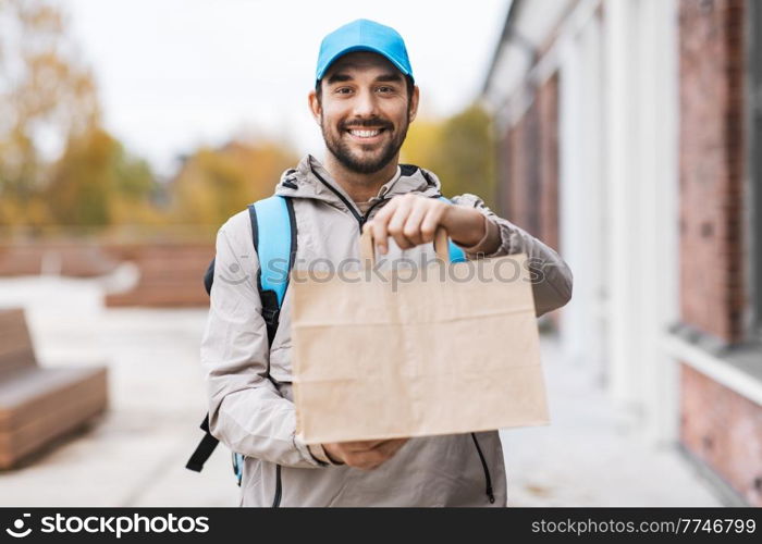 food shipping, profession and people concept - happy smiling delivery man with thermal insulated bag and order in city. happy delivery man with takeaway food in paper bag