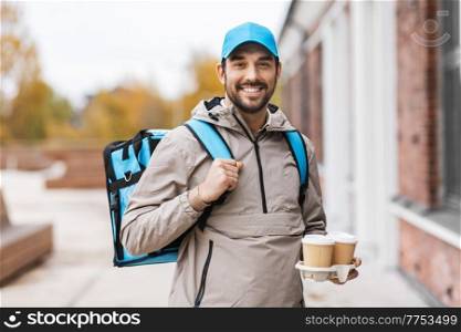 food shipping, profession and people concept - happy smiling delivery man with thermal insulated bag and takeaway paper coffee cups in city. happy delivery man with thermal bag and coffee