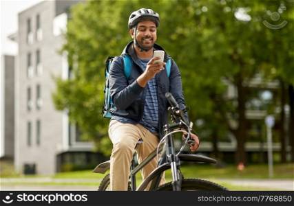 food shipping, profession and people concept - happy smiling delivery man with thermal insulated bag, smartphone and bicycle on city street. food delivery man with bag, smartphone and bicycle