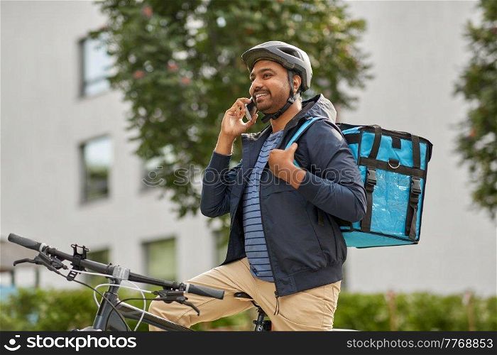 food shipping, profession and people concept - happy smiling delivery man with thermal insulated bag and bicycle on city street calling on smartphone. food delivery man with bag calling on smartphone