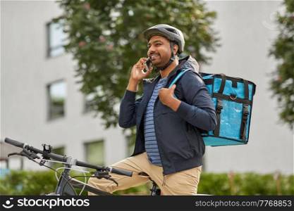 food shipping, profession and people concept - happy smiling delivery man with thermal insulated bag and bicycle on city street calling on smartphone. food delivery man with bag calling on smartphone