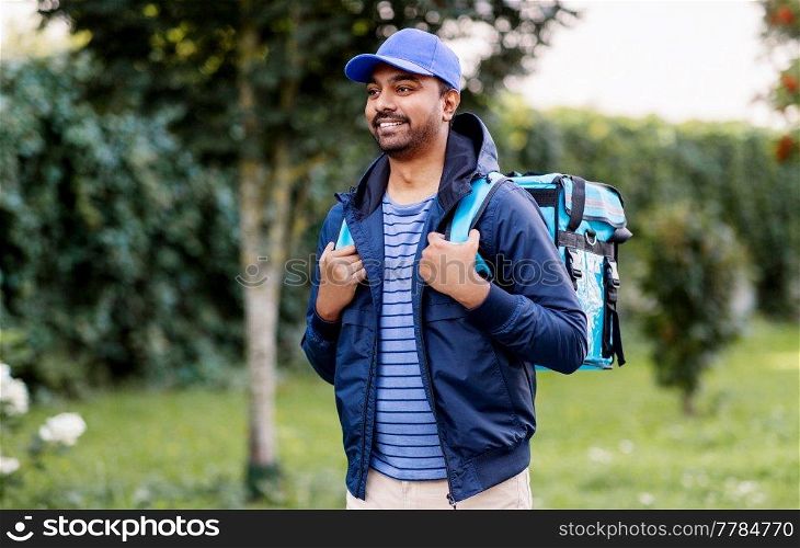 food shipping, profession and people concept - happy smiling indian delivery man with thermal insulated bag walking along street. indian delivery man with bag walking outdoors