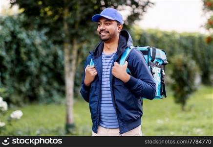 food shipping, profession and people concept - happy smiling indian delivery man with thermal insulated bag walking along street. indian delivery man with bag walking outdoors