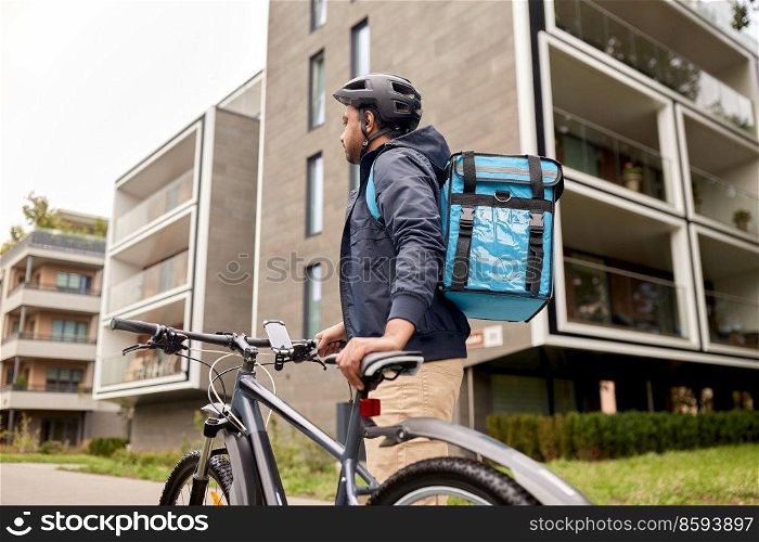 food shipping, profession and people concept - happy smiling indian delivery man with thermal insulated bag and bicycle on city street. indian delivery man with bag and bicycle in city