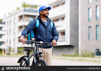 food shipping, profession and people concept - happy smiling indian delivery man with thermal insulated bag and bicycle on city street. indian delivery man with bag and bicycle in city