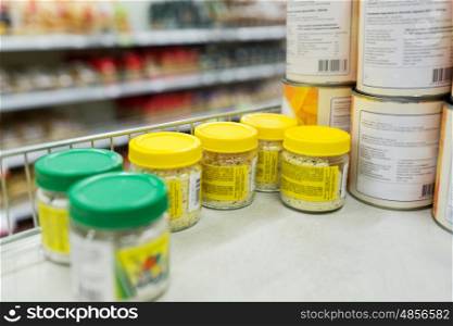 food, shopping and consumerism concept - jars with spices at grocery shelf
