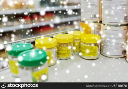 food, shopping and consumerism concept - jars with spices at grocery shelf over snow. jars with food or spices at grocery shelf