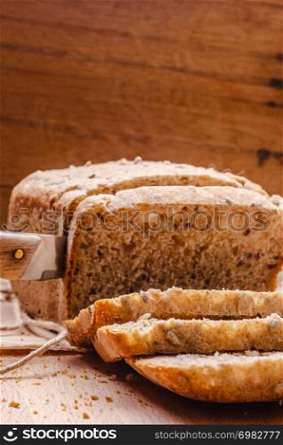 Food. Sliced whole wheat bread and knife on cutting board wooden background