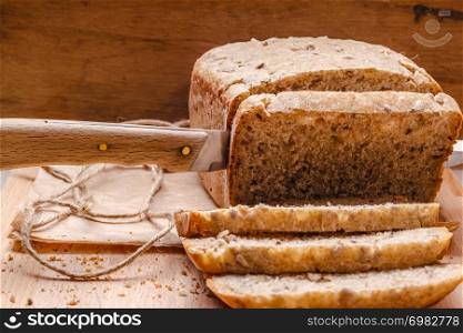 Food. Sliced whole wheat bread and knife on cutting board wooden background
