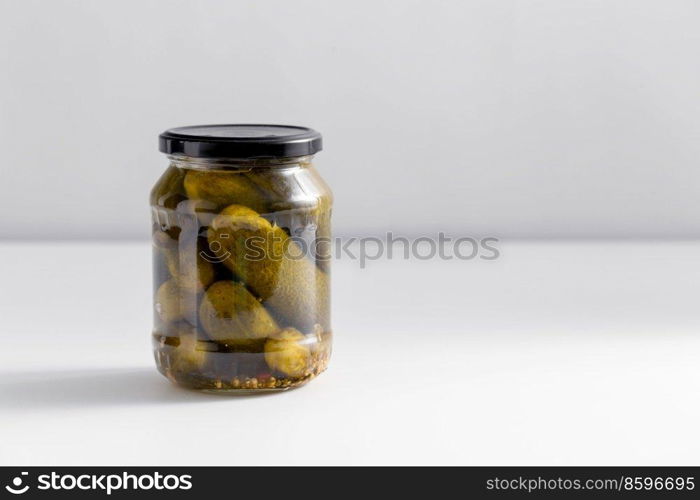 food, storage and preserve concept - close up of jar with pickled cucumbers on white table. close up of jar with pickled cucumbers on table
