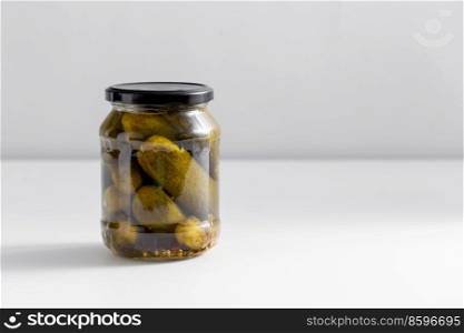 food, storage and preserve concept - close up of jar with pickled cucumbers on white table. close up of jar with pickled cucumbers on table
