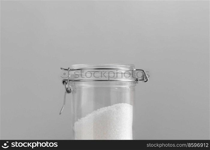food storage, cooking and unhealthy eating concept - close up of sea salt glass jars on grey background. close up of sea salt glass jars on grey background