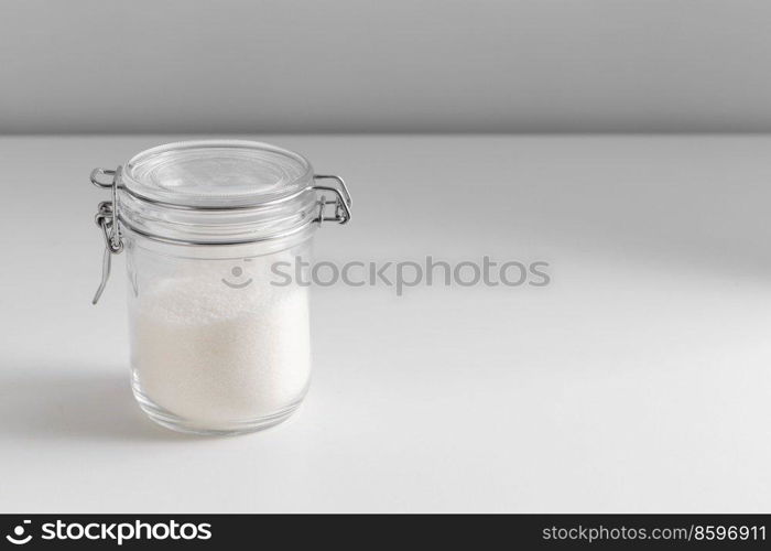 food storage, cooking and unhealthy eating concept - close up of white sugar glass jar on table. close up of white sugar glass jar on table