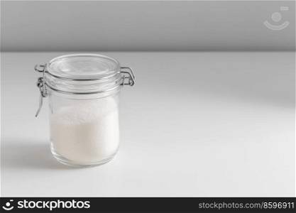 food storage, cooking and unhealthy eating concept - close up of white sugar glass jar on table. close up of white sugar glass jar on table